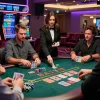 Engaged players enjoying a baccarat game at a modern 바카라사이트, vibrant atmosphere with dealer and colorful chips.