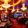 Permainan di kasino bbni4d yang menampilkan meja judi dan mesin slot berwarna cerah.