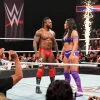 Xavier Woods and Paige interacting with fans at a live WWE wrestling event, vibrant attire, high-energy atmosphere.