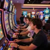 Players engaging with vibrant slot machines at a busy casino, showcasing agen slot excitement.